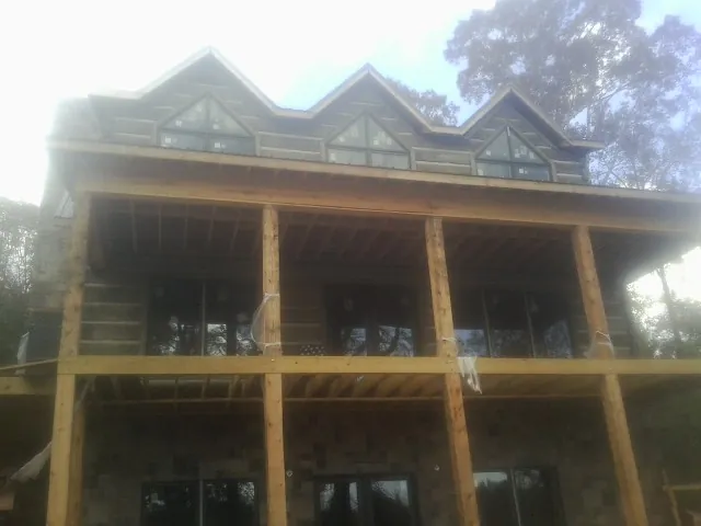 Dormers and porch framing on a large log home under construction — Roof Coating work by our crew in Advance