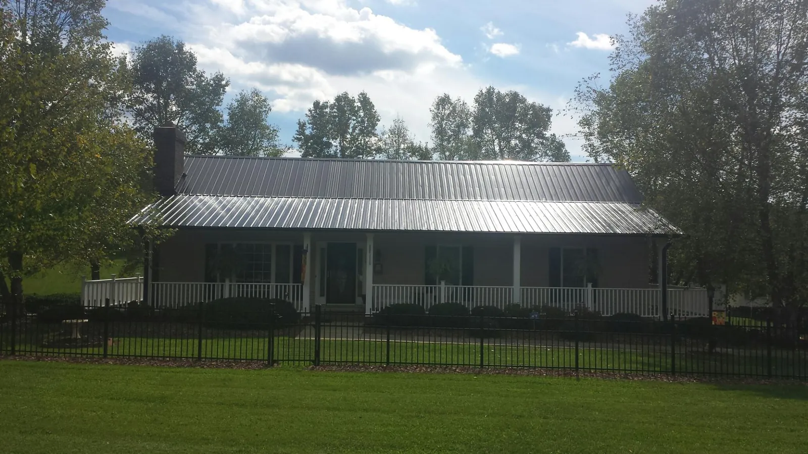 Gray metal roof on a brick ranch with a full width front porch — Gutter Guard Installation work by our crew in Advance